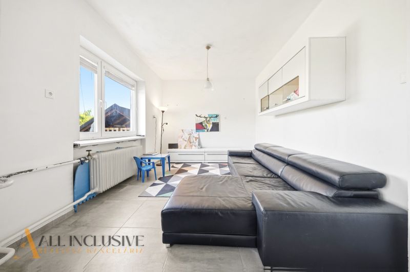 Living room in a family house with a sofa, children's chairs, and a large window.