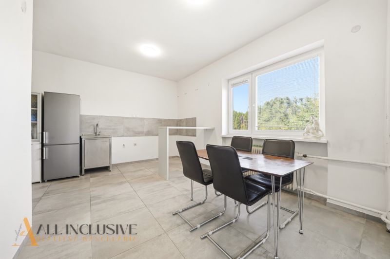Dining room in a family house with a simple kitchen unit and a dining table.