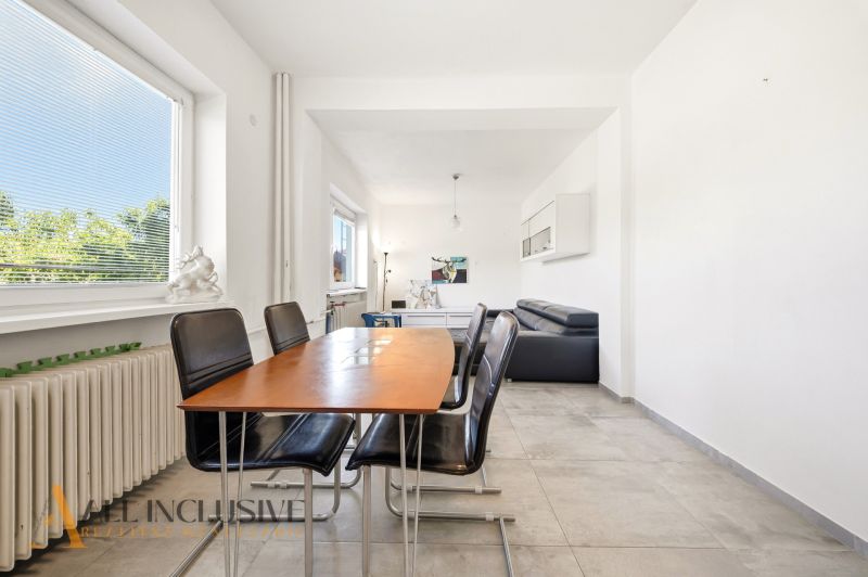 Dining area in a family house with black chairs and a large window.