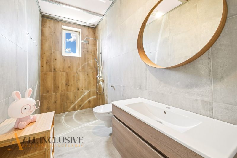 A bathroom in a family house with a wooden decor floor, a mirror, and a modern sink.