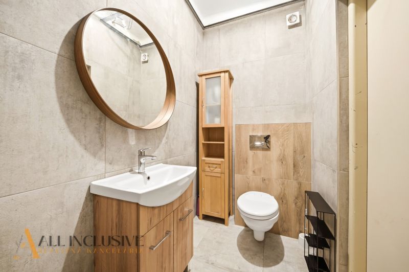 Bathroom in a family house with a round mirror and wooden decor on the walls.