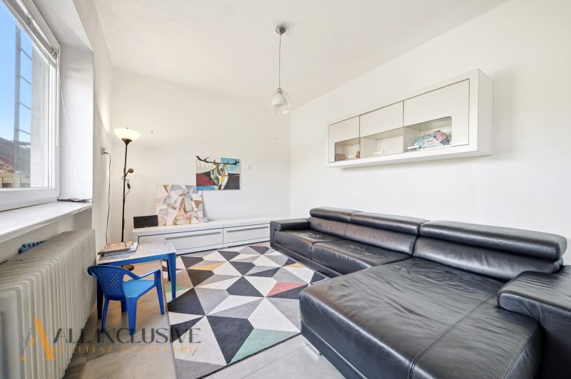 Living room with a black sofa, children's table, and geometric carpet in a family house.