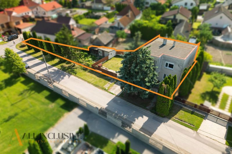 A family house in Topoľníky with a large plot lined with trees and an orange line.