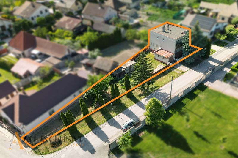 A family house in Topoľníky with a plot of land, bordered by greenery and an access road.