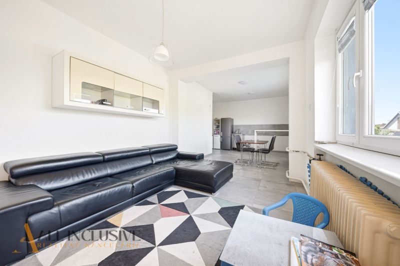 Living room in a family house with a black sofa and a dining area.