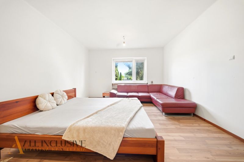 A bedroom in a family house with a red sofa and a wooden decor floor.