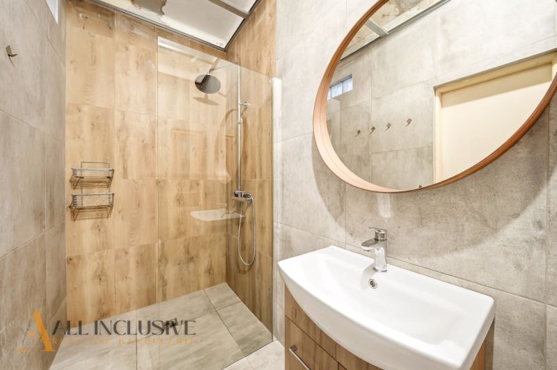 A bathroom in a family house with wooden decor and a round mirror.