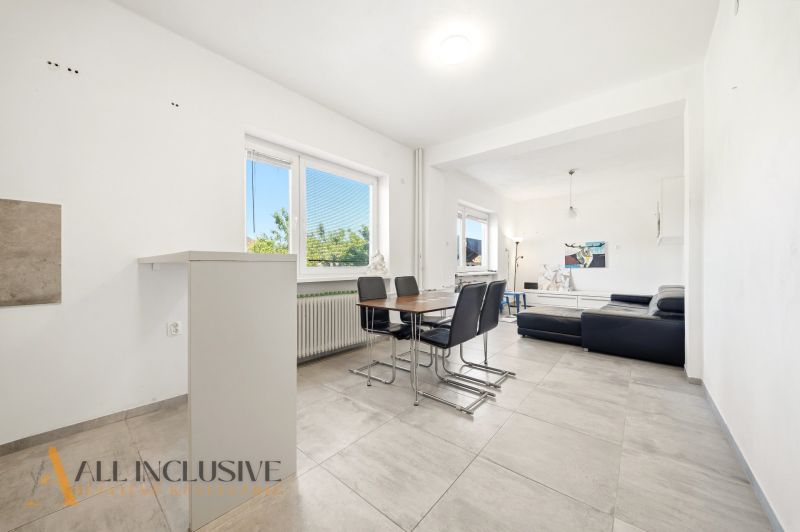 Dining area with dark furniture in a family house and living zone with a sofa.