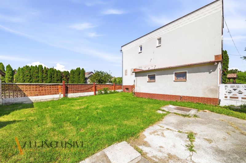 A garden at a family house in Topoľníky with a lawn and a brick fence.