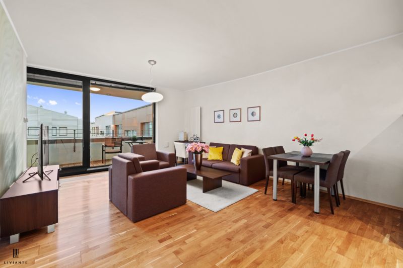Living room in a 2-room apartment with a wooden decor floor and a spacious terrace.