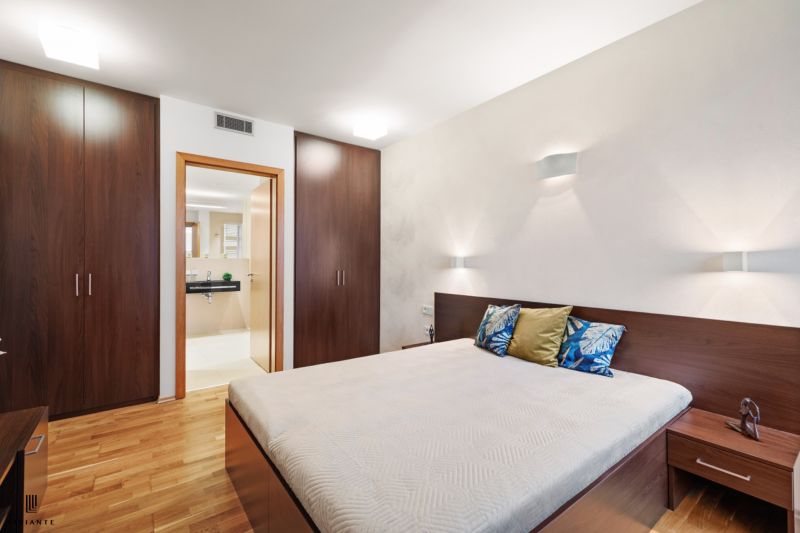A bedroom in a two-room apartment with a wooden decor floor and built-in wardrobes.