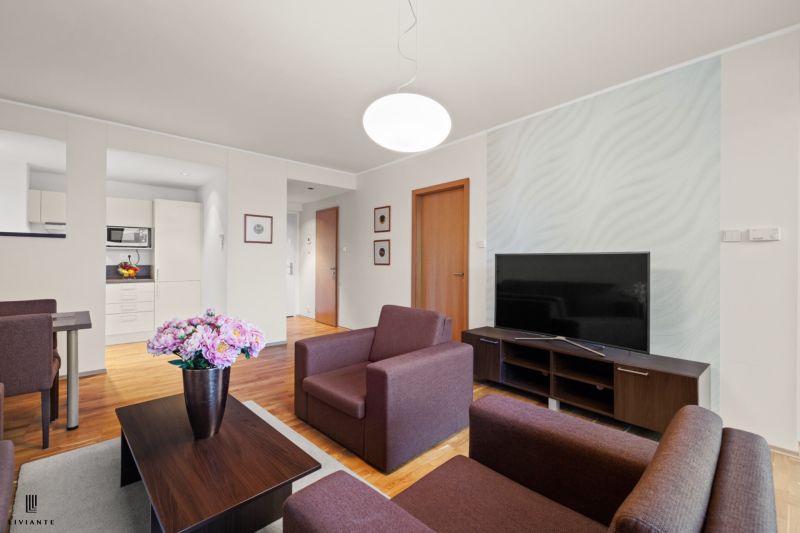 Living room in a two-room apartment with a wooden decor floor and modern furniture.