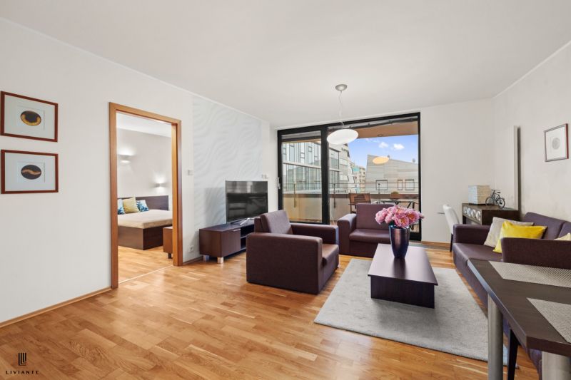 Living room in a two-room apartment with a wooden decor floor and a balcony.