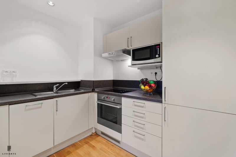 A kitchen in a 2-room apartment with white cabinets and a wood-patterned floor.