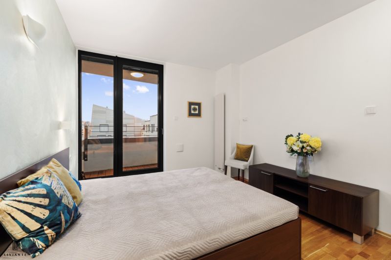 Bedroom with wood-patterned flooring, large windows, and a decorative planter.