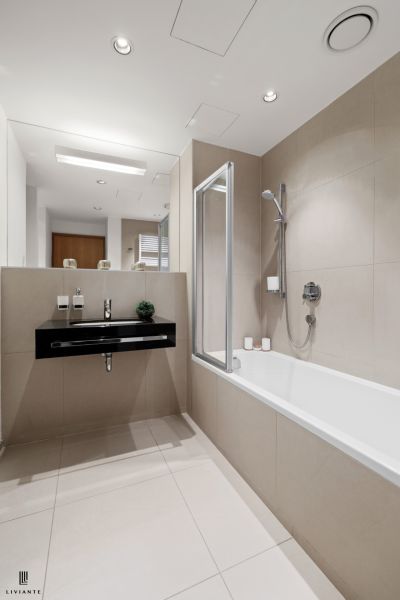 A bathroom in a 2-room apartment with a bathtub, sink, and separate faucet.