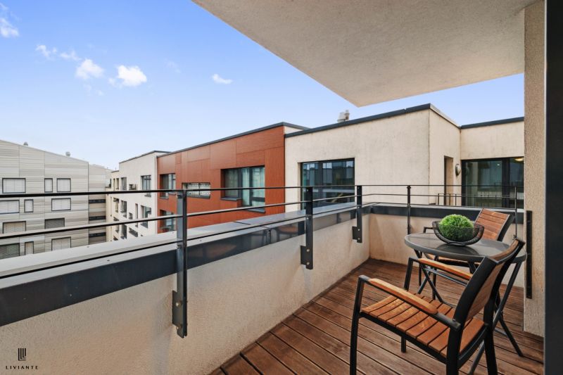 A balcony with wooden decor and furniture, view of the surrounding buildings.
