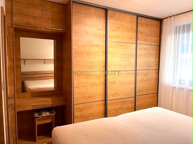 Bedroom with a large wardrobe and mirror, 2-room apartment with wooden decor flooring.