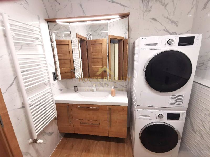 Bathroom in a 2-room apartment with a washing machine, sink, and retro radiator. Floor with wood decor.