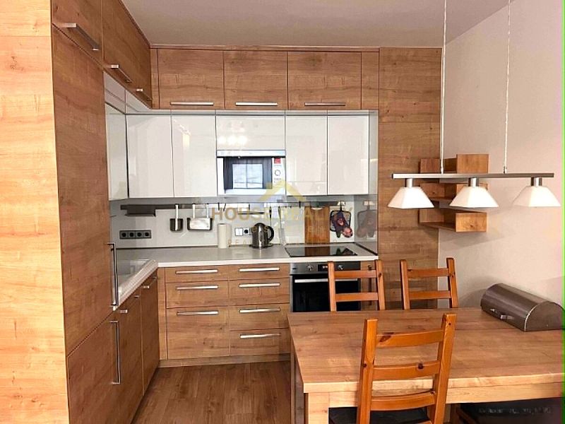 A kitchen in a 2-room apartment with white cabinets and wooden decor.