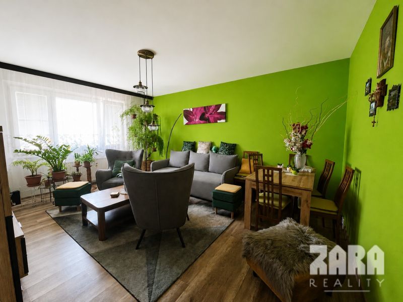 Living room in a 3-room apartment with a wooden decor floor and green walls.