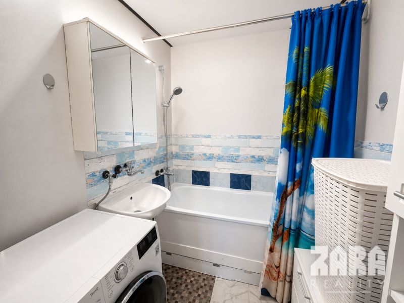 A bathroom in a 3-room apartment with a shower curtain featuring a palm motif.