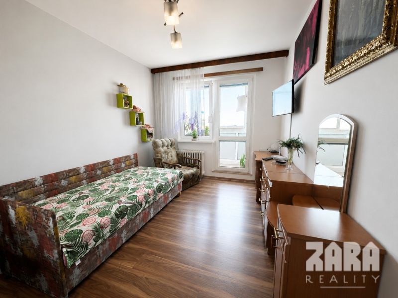 Living room in a three-room apartment with a wooden decor floor and a sofa.