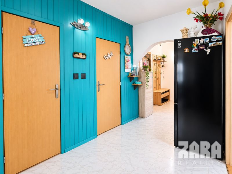 Colorful hallway in a 3-room apartment with wooden doors and a black refrigerator.