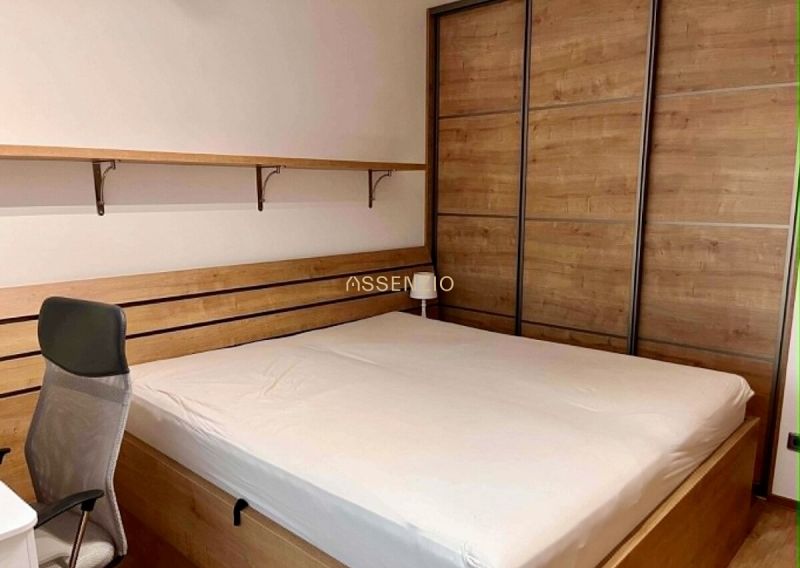 Bedroom in a 2-room apartment with a bed and a wardrobe, floor with wooden decor.