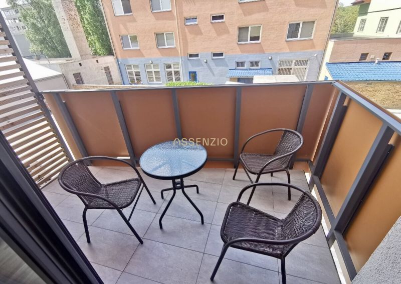 Balcony of a 2-room apartment with three chairs and a table, view of neighboring buildings.