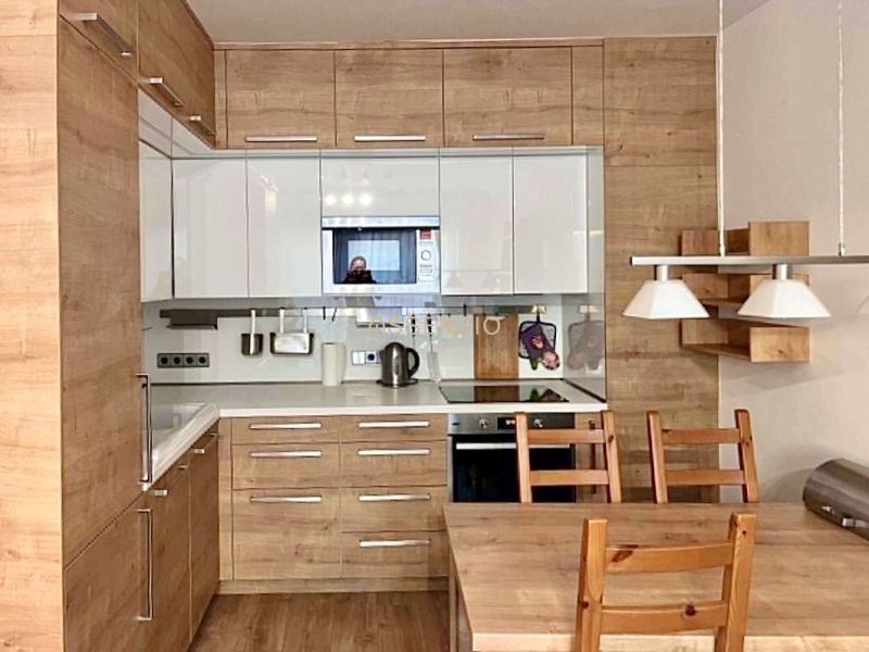 A kitchen in a 2-room apartment with a wooden decor and a dining table.