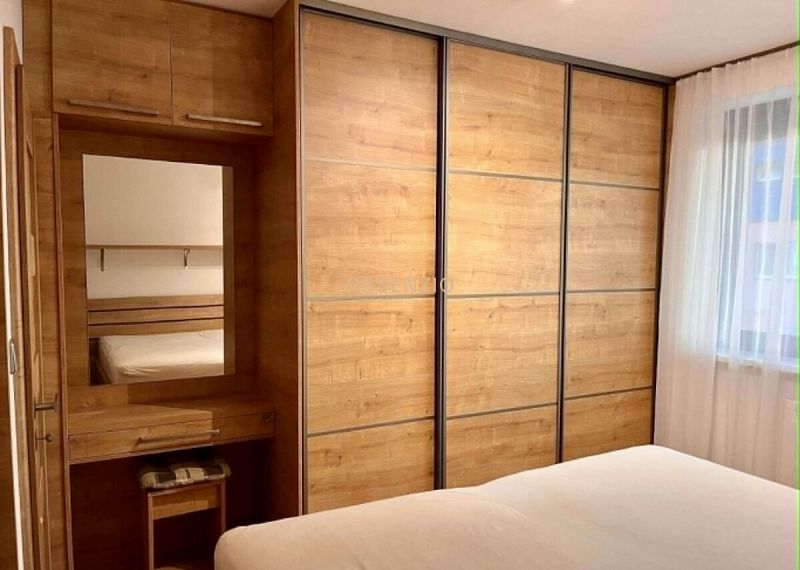 Bedroom in a 2-room apartment with a large wardrobe and a floor with a wooden decor.