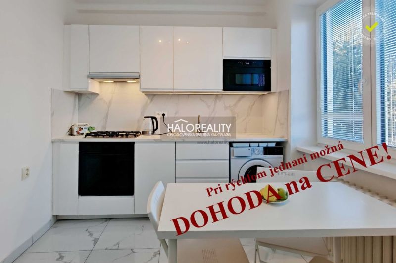 A kitchen in a 2-room apartment with white cabinets and marble tiles.
