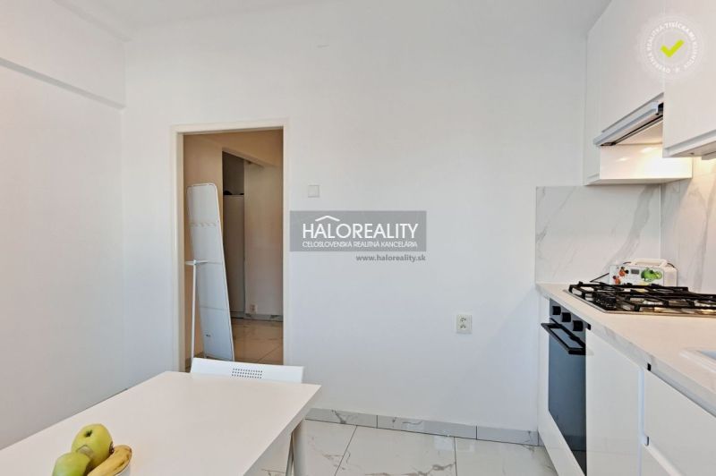 A kitchen in a 2-room apartment with a gas stove and a dining table.