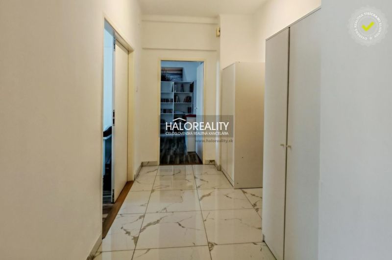 The hallway of a 2-room apartment with white walls and tiles, wardrobes on the sides.