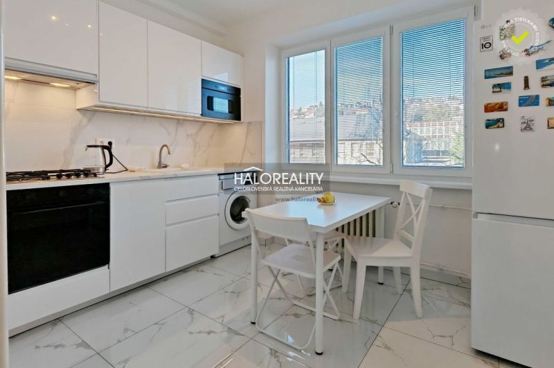 A bright kitchen in a 2-room apartment with white cabinets, a stove, and dining seating.
