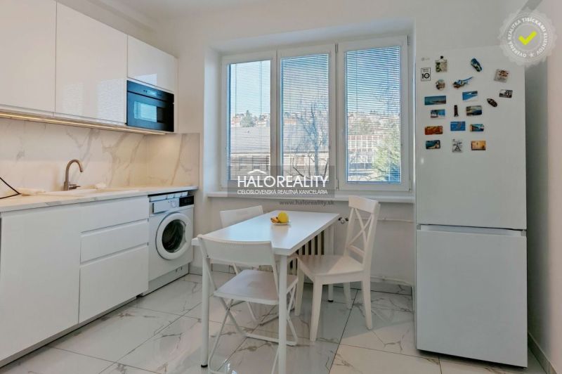 A kitchen in a 2-room apartment with light furniture and a large window.