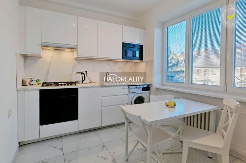 A kitchen in a 2-room apartment with white cabinets and a dining table.