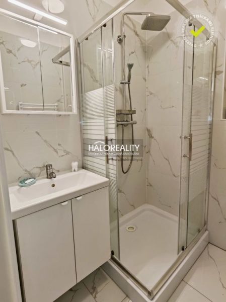 A bathroom in a 2-room apartment with a sink, shower, and marble tiles.