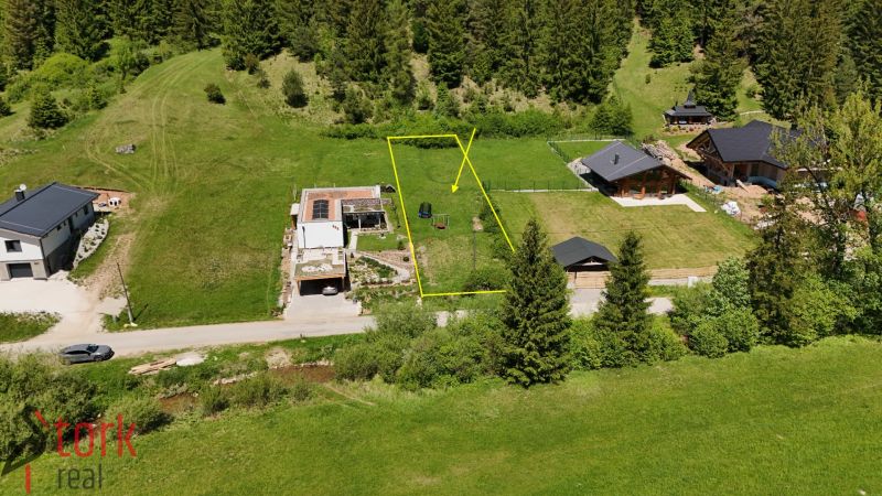 Residential plots in Rajecká Lesná surrounded by greenery and coniferous forests.