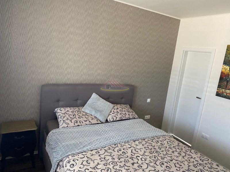 Bedroom in a family house with wallpaper, bed, and nightstand.