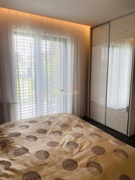 A bedroom in a family house with a large bed, a wardrobe, and curtains on the windows.