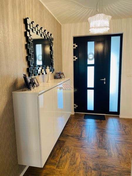 Entrance hall in a family house with a wooden decor floor and a mirror on the wall.