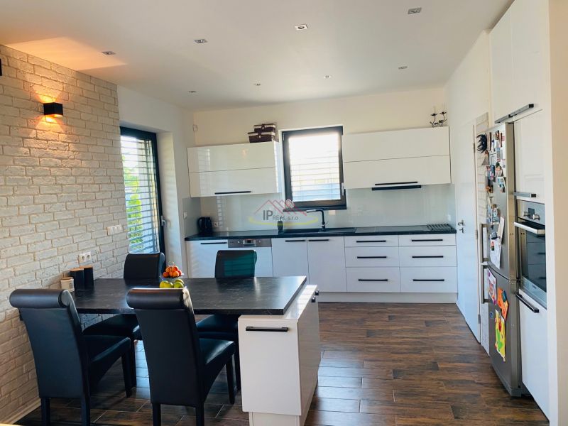 A kitchen in a family house with white cabinets, a table, and a wooden decor floor.