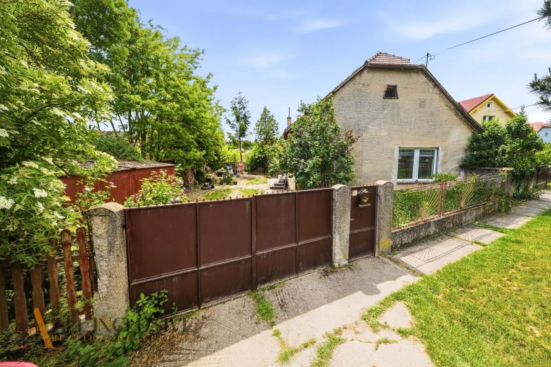 A family house in Lehnice with a gate and a garden, surrounded by greenery and a grassy area.