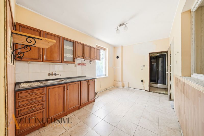 A kitchen with tiles and wooden cabinets in a family house.