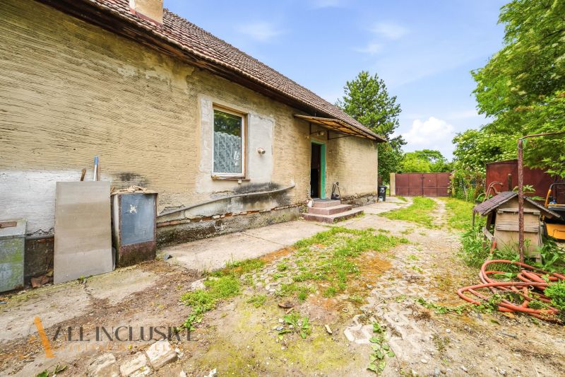 The exterior of an older family house in Lehnice, with an unkempt yard and a clay facade.