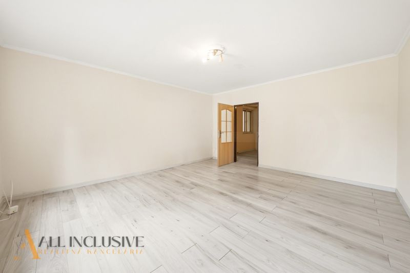 A spacious room with a wooden-patterned floor in a family house.