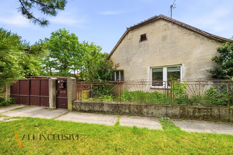 A family house in Lehnice with a gate, a fence, and trees in the yard.
