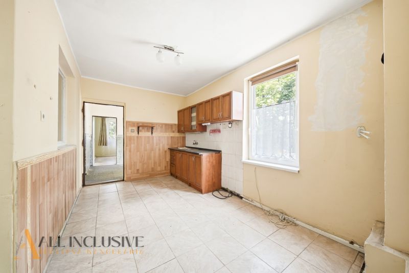 A kitchen in a family house with white tiles and wooden decor cabinets.